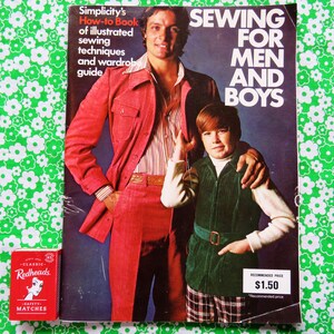 May include: A vintage sewing book titled "Sewing for Men and Boys" with a red cover featuring two people. The book is next to a box of Redheads matches on a green floral patterned background.