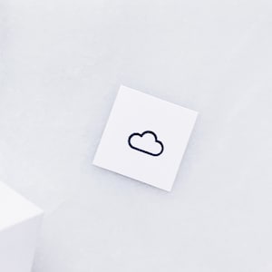 May include: A white card with a black cloud icon drawn on it. The card is on a white surface.