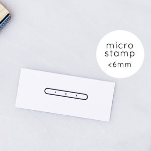 May include: A white card with a black line and three small black dots on it. The card is labeled "micro stamp <6mm".