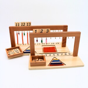 May include: Wooden counting frame with beads and number tiles. The frame has two levels, each with a set of beads and number tiles. The beads are arranged in a pyramid shape and the number tiles are arranged in a row. The frame is made of natural wood and has a light brown finish.