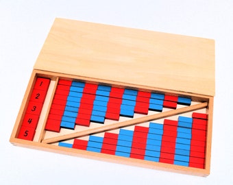 May include: A wooden box containing a set of red and blue wooden blocks, arranged in a staircase pattern. The blocks are numbered 1 through 5, and the box has a lid.