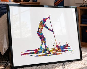 May include: Framed art print featuring a colorful watercolor illustration of a person paddleboarding. The artwork depicts a figure in motion, using a paddle on a board, with vibrant splashes of red, blue, yellow, and green. The print is set against a white background.