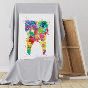 May include: A colorful watercolor painting of a tooth. The tooth is filled with vibrant paint splatters in shades of blue, green, yellow, red, and purple. The artwork is displayed on a white canvas, leaning against a draped surface.