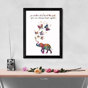 May include: A framed print with a colorful watercolor painting of an elephant with butterflies flying around it. The quote "No matter how hard the past, you can always begin again." is printed below the elephant.