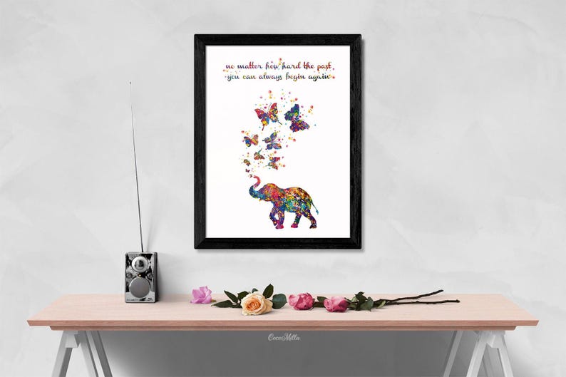 May include: A framed print with a colorful watercolor painting of an elephant with butterflies flying around it. The quote "No matter how hard the past, you can always begin again." is printed below the elephant.