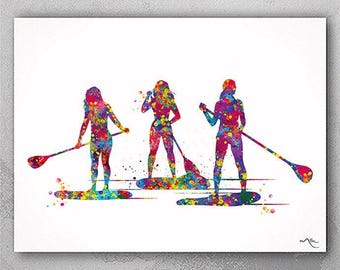 May include: Three women stand on paddleboards, holding paddles. The women are painted in a watercolor style with splashes of pink, blue, green, yellow, and orange.