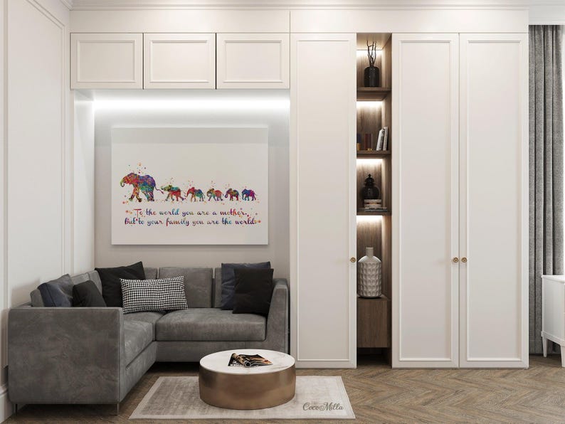 May include: A watercolor painting of a line of elephants with the text "To the world you are a mother, but to your family you are the world." The painting is framed and hanging on a white wall in a living room setting.