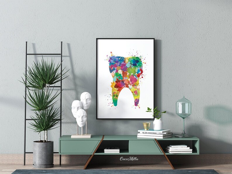 May include: A framed watercolor print of a tooth, featuring a colorful splatter design. The artwork is displayed on a wall above a green cabinet with decorative items. The overall theme is dental art.