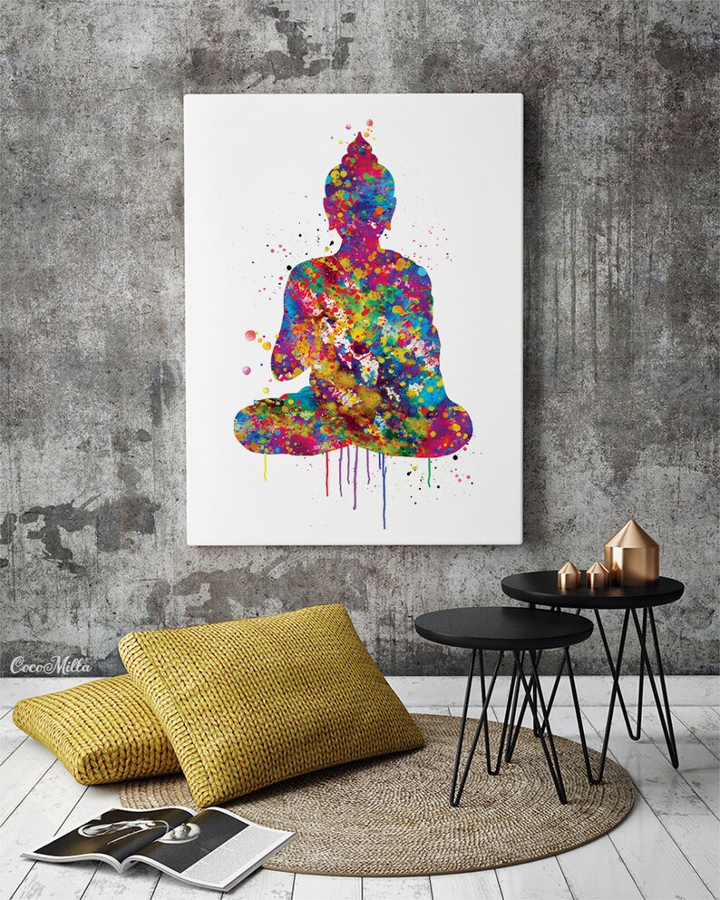 May include: A colorful watercolor painting of a seated Buddha figure. The artwork features a vibrant mix of colors, including blue, yellow, red, and green, with paint splatter effects. The image is displayed on a white canvas, mounted on a gray wall.