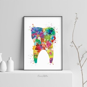 May include: A framed print featuring a colorful watercolor illustration of a tooth. The tooth is filled with vibrant splashes of red, yellow, blue, and green. The artwork is displayed on a white shelf with minimalist white vases.