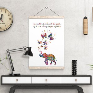 May include: A white canvas print with a colorful elephant blowing butterflies. The text on the print reads "No matter how hard the past, you can always begin again."