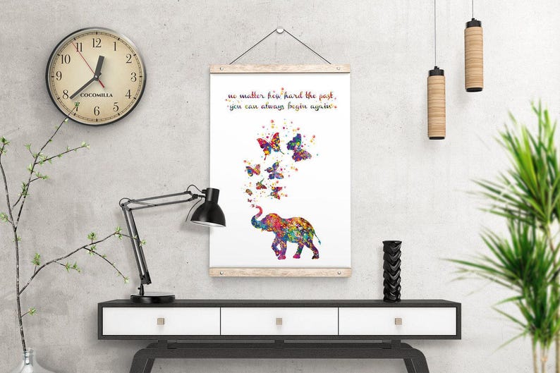 May include: A white canvas print with a colorful elephant blowing butterflies. The text on the print reads "No matter how hard the past, you can always begin again."