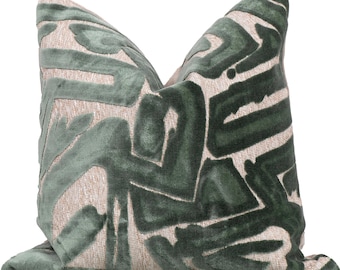 May include: Decorative throw pillow with a geometric design. The pillow features a soft, textured fabric in a light beige color, overlaid with a dark green, abstract pattern. The pillow is square and has a plush appearance, suitable for home decor.