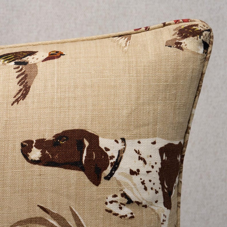 May include: A beige throw pillow with a brown and white dog and a brown and white bird design.