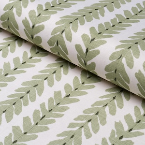 May include: White fabric with a repeating pattern of green leafy branches. The fabric is folded in half, showing the pattern on both sides.