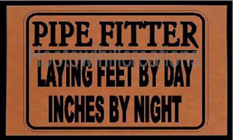 May include: A brown leather sign with black text that reads "Pipe Fitter Laying Feet By Day Inches By Night".