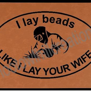 May include: A brown leather patch with a black oval graphic. The graphic features a welder with a welding torch and the text "I lay beads like I lay your wife".