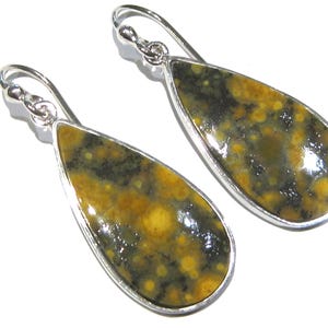 Puede incluir: Un par de pendientes en forma de lágrima con un engaste de metal plateado. Los pendientes presentan un patrón moteado de amarillo, marrón y negro. Cierre de gancho.