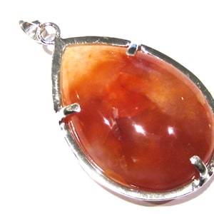 Puede incluir: Un colgante en forma de lágrima con una piedra de cornalina roja engastada en un marco de plata.