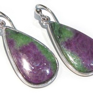 May include: A pair of teardrop-shaped earrings with a silver-colored metal setting. The earrings feature a polished stone with a mix of green and purple hues. The earrings are designed with a hook closure.
