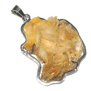 Puede incluir: Colgante plateado con una formación de cristal natural de color marrón claro. El cristal está encerrado en un marco de metal plateado, con un lazo para una cadena. El colgante tiene una forma orgánica única.