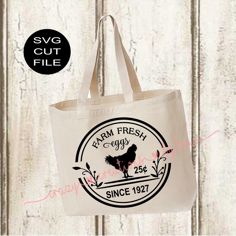 May include: A white canvas tote bag with black handles and a black circular design featuring the text "Farm Fresh Eggs" and a silhouette of a rooster. The design also includes the text "Since 1927" and "25c".