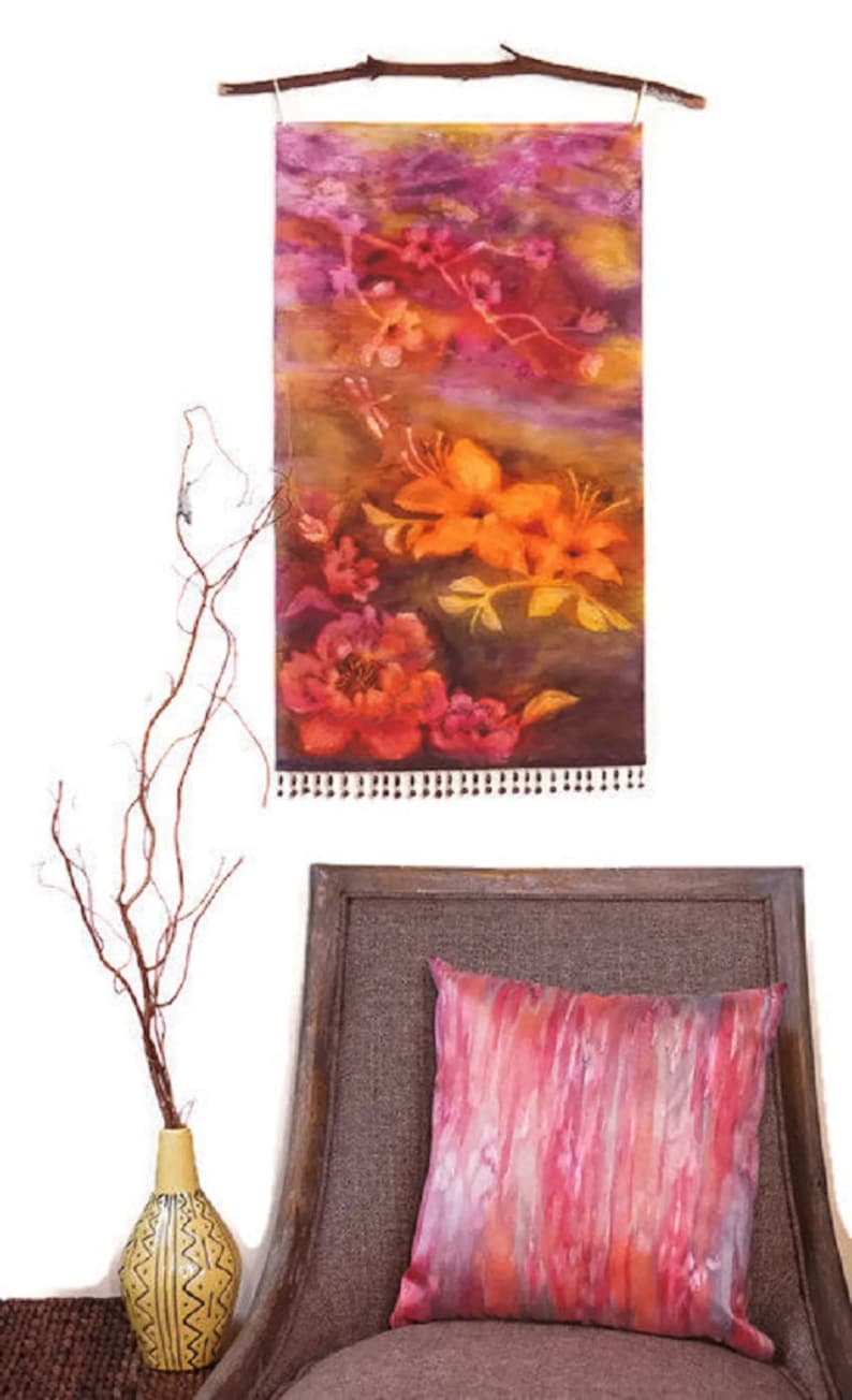 May include: A wall tapestry with a floral design featuring orange, pink, and purple flowers. The tapestry is hanging on a wooden branch and has a fringe border.