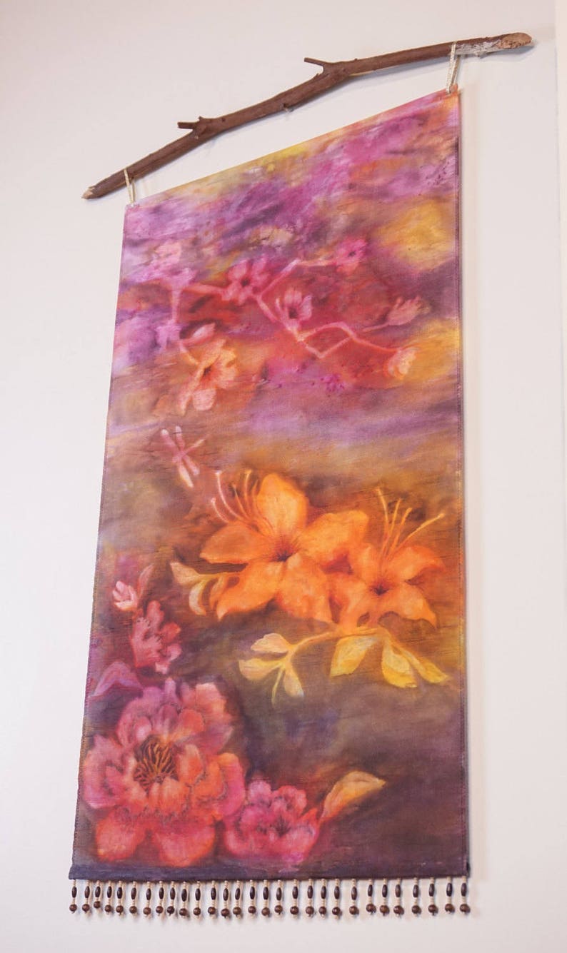 May include: A colorful wall hanging with a floral design. The hanging features a variety of flowers in shades of pink, orange, and yellow. The hanging is accented with a beaded fringe.