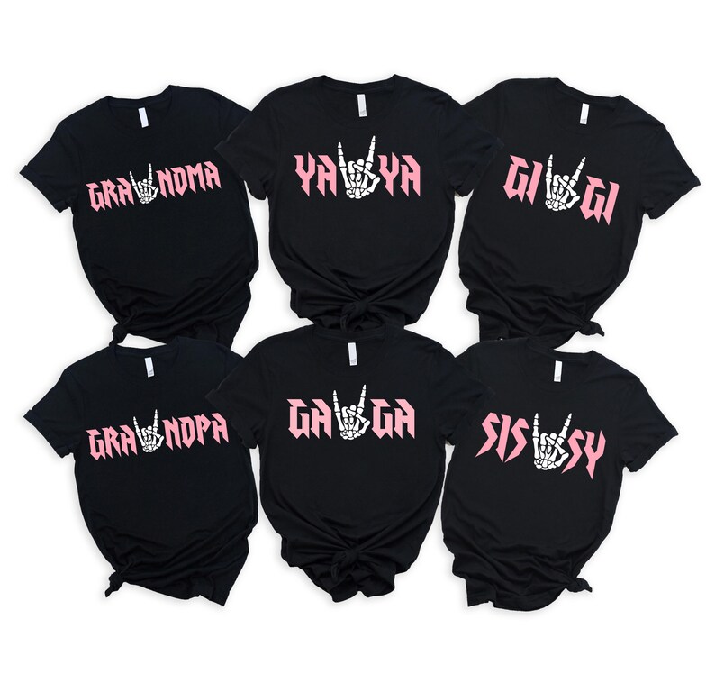 May include: Six black t-shirts with pink text and a hand symbol. The shirts read "Gra'noma", "Ya'Ya", "Gi'Gi", "Gra'npa", "Ga'Ga", and "Sissy".