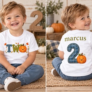 May include: A white short-sleeve t-shirt featuring a graphic of the word TWO with a blue plaid letter T, a green letter W, and an orange pumpkin as the letter O, surrounded by autumn leaves. The back displays the name marcus and a large blue plaid number 2.