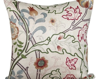 May include: A square throw pillow with a cream-colored base featuring an intricate embroidered botanical pattern in shades of red, green, and light blue. The design includes stylized leaves and flowers with visible stitching. The text Pretty Cushions is printed in black at the bottom right.
