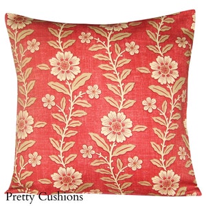 Puede incluir: Cojín de decoración rojo y crema con estampado floral y tejido sutilmente texturizado. El cojín presenta un patrón repetitivo de flores y hojas estilizadas.