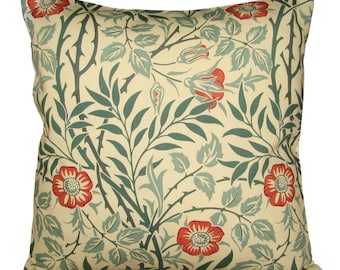 May include: A cream-colored throw pillow with a floral pattern featuring red roses and green leaves. The pillow has a square shape and a subtle texture.