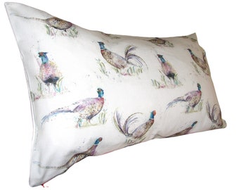 May include: A rectangular throw pillow featuring a repeating watercolor print of male pheasants with iridescent blue heads, brown bodies, and long tail feathers on a white background. The fabric has a visible texture and a side zipper.