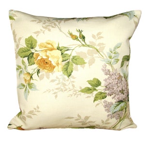 May include: A cream-colored throw pillow with a floral pattern featuring yellow roses and purple lilac flowers on a beige background.