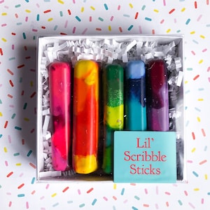 May include: A set of six colorful crayon sticks in a white box with a blue label that reads "Lil' Scribble Sticks".