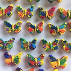 May include: A collection of colorful butterfly-shaped crayons. The crayons are made of wax and have a variety of colors, including red, orange, yellow, green, blue, and purple.