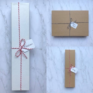 May include: Three wrapped gifts with twine and personalized tags. The gifts are wrapped in white, brown, and brown paper. The tags say "Nathan", "Hey Boo!" and "Awrey".