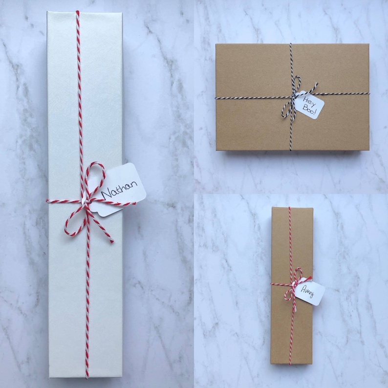 May include: Three wrapped gifts with twine and personalized tags. The gifts are wrapped in white, brown, and brown paper. The tags say "Nathan", "Hey Boo!" and "Awrey".