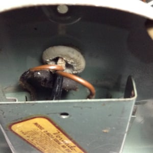 Puede incluir: Primer plano del interior de un ventilador de techo con un cable marr&oacute;n y una toma de cer&aacute;mica blanca. El ventilador est&aacute; etiquetado como "Tornado" y tiene un n&uacute;mero de modelo.