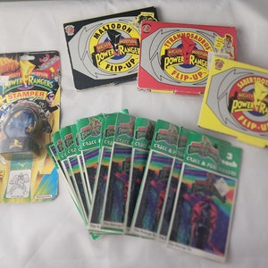 May include: A collection of Mighty Morphin Power Rangers toys and stickers.  The items include a flip-up book, a stamper, and a pack of stickers.  The toys are all green and yellow with the Power Rangers logo.
