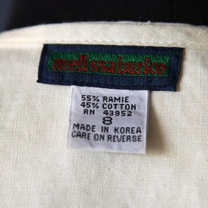 May include: A white tag with black and green trim and red text that reads "melissa burke". Below the tag is a smaller white tag with black text that reads "55% RAMIE 45% COTTON RN 43952 8 MADE IN KOREA CARE ON REVERSE".