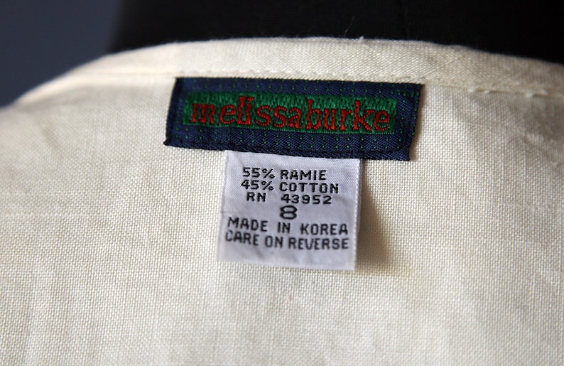 May include: A white tag with black and green trim and red text that reads "melissa burke". Below the tag is a smaller white tag with black text that reads "55% RAMIE 45% COTTON RN 43952 8 MADE IN KOREA CARE ON REVERSE".