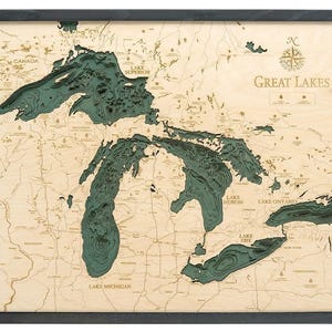 May include: A framed 3D wooden bathymetric map of the Great Lakes featuring layered light wood topography and deep teal water depths. The map includes engraved labels for Lake Superior, Michigan, Huron, Erie, and Ontario, plus a compass rose.