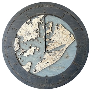 May include: A gray wooden tide clock with a map of Hilton Head, South Carolina. The clock face shows the tide levels, with high tide at the top and low tide at the bottom. The clock hands are black and point to the current tide level.