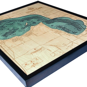 K&ouml;nnte beinhalten: Eine Holzkarte eines Sees mit einem blauen Rahmen. Der See ist in Relief geschnitzt und in T&uuml;rkisfarben bemalt. Die Karte tr&auml;gt die Aufschrift "Higgins Lake" in der oberen linken Ecke.