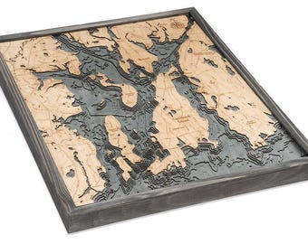May include: A square, framed 3D bathymetric wood map featuring light tan landmasses and dark gray water depths. The layered construction displays intricate coastal topography, islands, and nautical labels, all enclosed within a dark gray wooden frame.
