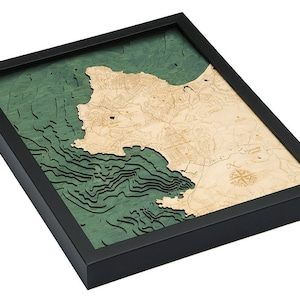 May include: A framed wooden map of a coastal area with green and brown wood tones. The map features detailed contour lines and a compass rose.