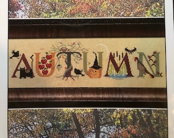May include: A cross stitch pattern for a fall-themed design featuring the word "AUTUMN" with various autumnal elements, including a witch's hat, a pumpkin, and a bird. The pattern is from The Cricket Collection, No. 304.