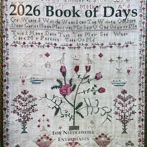 May include: A framed antique needlework sampler, featuring the text "2026 Book of Days" and various embroidered motifs. The sampler includes floral designs, birds, and decorative borders, with the text "For Needlework Enthusiasts".